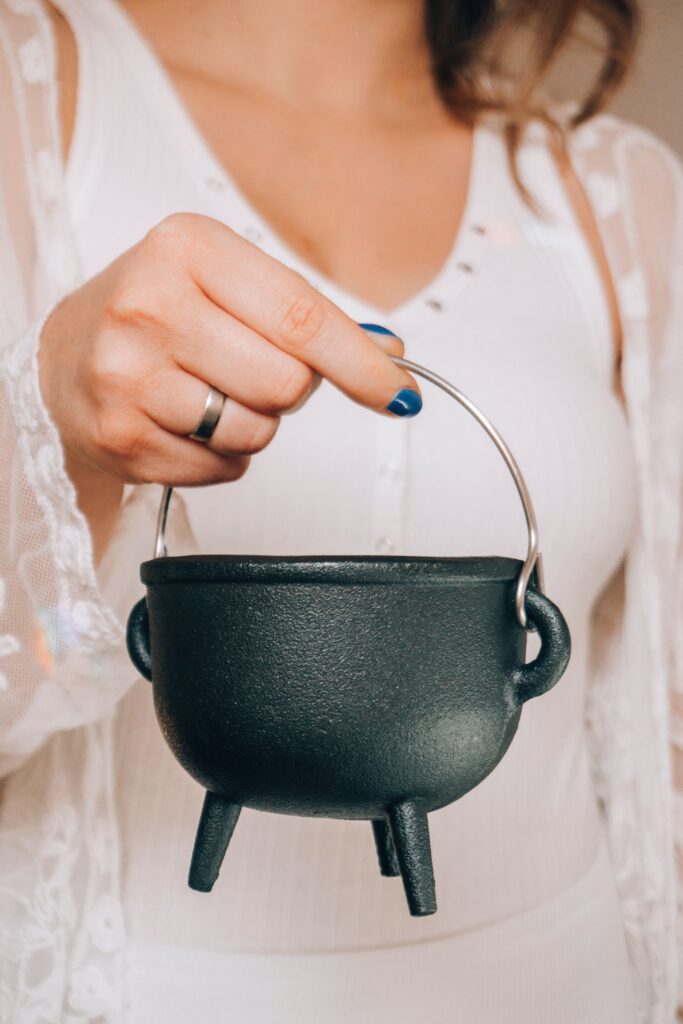 Woman in white clothing holding a cauldron